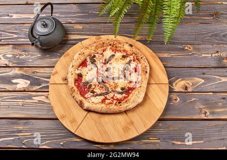 Pizza napoli auf einem Holzständer Stockfoto
