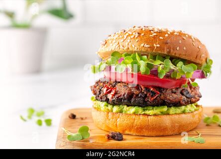 Gesunder, pflanzenbasierter Burger aus schwarzen Bohnen mit Avocado und Microgreens Stockfoto