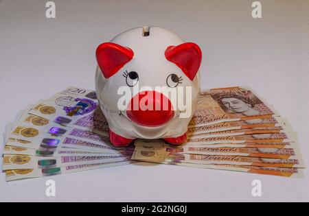 Sparschwein mit britischen Pfund Sterling Banknoten und Bargeld Stockfoto