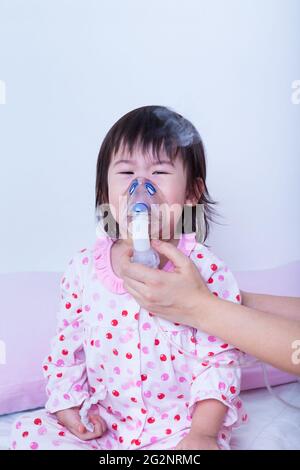 Der Arzt hilft kleinen asiatischen (thailändischen) Mädchen, die Atemwege (Kind war Bronchitis), Inhalationstherapie, Kind war Bronchitis und Weinen, auf weißem Backgro Stockfoto