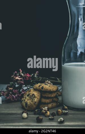 Vertikale Aufnahme von leckeren Keksen, Nüssen und einem Glas Milch auf dem Tisch Stockfoto