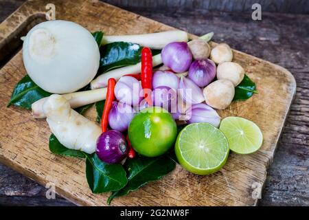 Stillleben Kaffir Limettenblatt, Zitrone, Zitronengras, Galgant, Chili, Zwiebeln und Strohpilze Kräuter und würzige Zutaten Thai-Essen (tom Yum) über Hacken Stockfoto