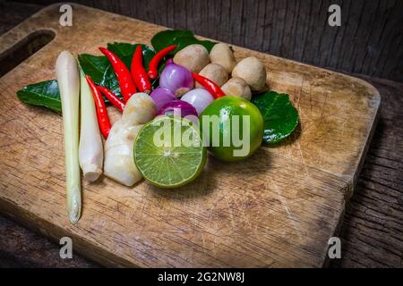 Stillleben Kaffir Limettenblatt, Zitrone, Zitronengras, Galgant, Chili, Zwiebeln und Strohpilze Kräuter und würzige Zutaten Thai-Essen (tom Yum) über Hacken Stockfoto