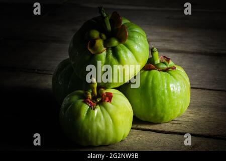 Stillleben garcinia atroviridis frische Früchte auf altem Holzhintergrund. Thailändisches Kraut und saurer Geschmack viel Vitamin C für gute Gesundheit. Low-Key-Bildstil Stockfoto