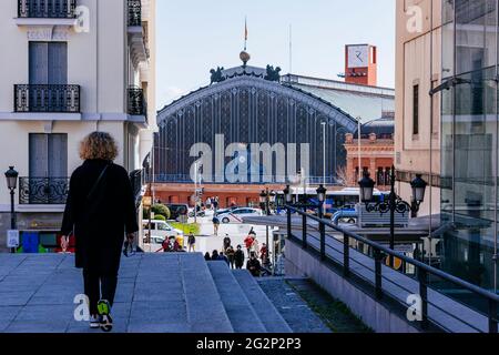 Frau, die auf der Santa Isabel Straße in Richtung Emperador Carlos V Platz geht, im Hintergrund der Atocha Bahnhof. Madrid, Comunidad Stockfoto