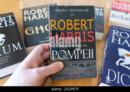 Eine Männerhand, die ein Taschenbuch von Pompeji hält, einem historischen Roman des englischen Schriftstellers Robert Harris Stockfoto