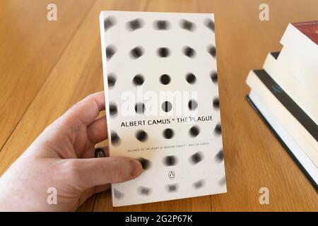 Die Hand eines Mannes, der ein Taschenbuch der Pest hält, ein Roman des französischen Autors Albert Camus Stockfoto