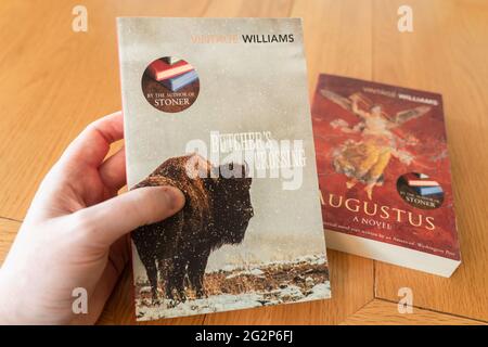 Eine Männerhand, die ein Taschenbuch von Butcher's Crossing hält, einem Roman des amerikanischen Autors John Williams Stockfoto