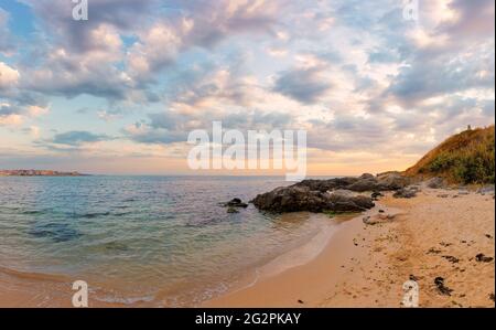 Sommerurlaub Landschaft am Meer bei Sonnenaufgang. Ruhiges Wasser wäscht Sandstrand. Dramatische Wolken über Horizont im Morgenlicht am Himmel Stockfoto