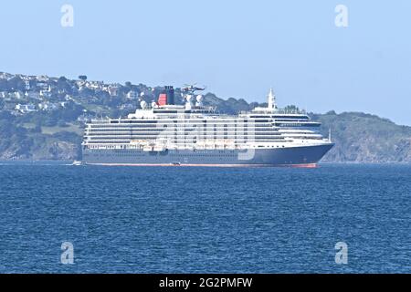 Brixham, Großbritannien. 12th. Juni 2021. UK.Brixham Devon. Während der Covid-19-Einschränkungsbedingungen schwebt Ein Küstenwache-Hubschrauber vor dem MS Queen Victoria Cunard Line-Kreuzschiff, während er auf See in der Brixham Bay festmacht. ? Bildquelle: Robert Timoney/Alamy Live News Stockfoto