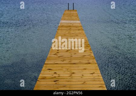 Blick auf einen langen hölzernen Pier, der in das klare Meerwasser führt Stockfoto