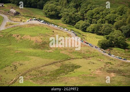 Autos parkten an einem belebten Sommernachmittag in Buttermere, Lake District, Großbritannien, am Straßenrand. Stockfoto