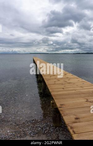 Blick auf einen langen hölzernen Pier, der in das klare Meerwasser führt Stockfoto