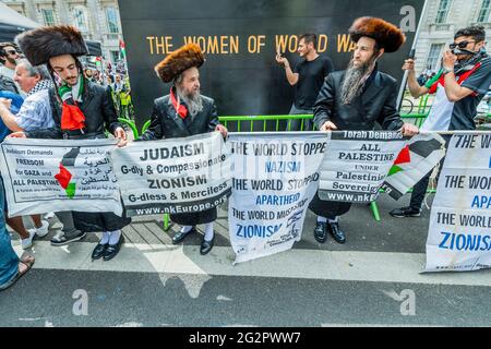 London, Großbritannien. Juni 2021. Orthodoxe Juden zeigen ihre Unterstützung und brennen eine israelische Flagge, während sie "mit Israel singen" - Palästinenserprotest vor der Downing Street in Whitehall, zeitlich begrenzt, um das Thema während des G7-Gipfels anzusprechen. Die Menschen sind gegen Israels jüngste Pläne, die palästinensischen Bewohner Jerusalems und den daraus resultierenden Konflikt, der in der Region entstanden ist, zu verlagern. Der Protest wurde von der palästinensischen Solidaritätskampagne UK, CND, Stop the war und den Freunden von Al Aqsa organisiert. Kredit: Guy Bell/Alamy Live Nachrichten Stockfoto