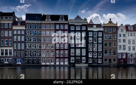 Amsterdam, Niederlande - 19. Mai 2021: Blick auf die ikonischen Häuser am Ufer des Damrak in der Innenstadt von Amsterdam Stockfoto