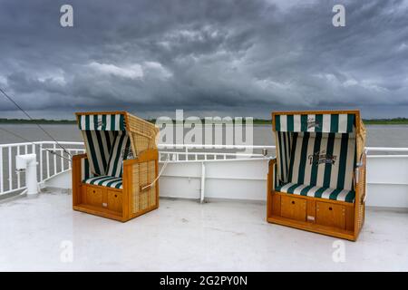 Brunsbüttel, Deutschland - 25. Mai 2021:komfortable Strandkörbe auf dem Panorama-Freideck einer Passagierfähre über die Elbe Stockfoto