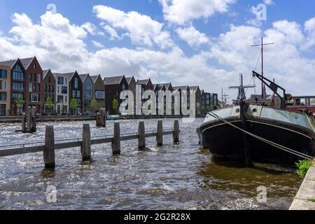 Haarlem, Niederlande - 21. Mai 2021: Reihe von bunten Häusern auf den Kanälen von Haarlem mit einem alten Flussschiff im Vordergrund Stockfoto