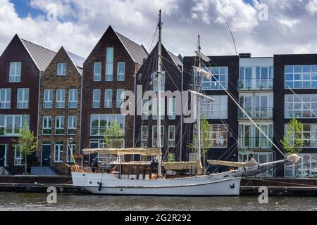 Haarlem, Niederlande - 21. Mai 2021: Reihe von bunten Häusern auf den Kanälen von Haarlem mit einem alten Flussschiff im Vordergrund Stockfoto