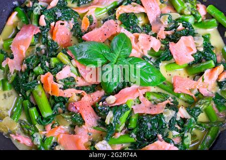 Spinat mit Lachs, Blauschimmelkäse und Spargel in einer Pfanne Stockfoto