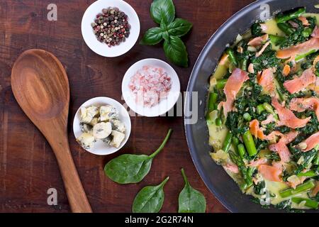 Spinat mit Lachs, Blauschimmelkäse und Spargel in einer Pfanne Stockfoto