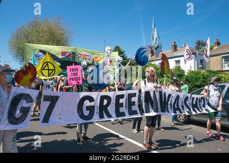 Falmouth, Cornwall, Großbritannien 2021 12. Juni ‘Aussterbungsrebellion marschiert aus Protest gegen die „Greenwashing“-Politik von Wirtschaft und Regierung beim G7-Gipfel. Die roten Rebellen führten den marsch durch das Stadtzentrum, zusammen mit den Ärzten von XR und schmutzigen Wäschern, und endeten am Medienzentrum. Stockfoto