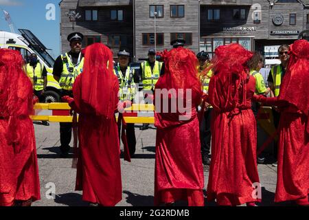 Falmouth, Cornwall, Großbritannien 2021 12. Juni ‘Aussterbungsrebellion marschiert aus Protest gegen die „Greenwashing“-Politik von Wirtschaft und Regierung beim G7-Gipfel. Die roten Rebellen führten den marsch durch das Stadtzentrum, zusammen mit den Ärzten von XR und schmutzigen Wäschern, und endeten am Medienzentrum. Stockfoto