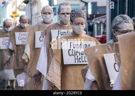 Falmouth, Cornwall, Großbritannien 12. Juni 2021 Extinction Rebellion Demonstranten kleiden sich als G7-Gipfel der „Büßer“. Die Büßer basieren auf der mittelalterlichen Idee der Sühne für Übertretungen gegen die Gemeinschaft, sie tragen die Verbrechen der heutigen Welt in ihre eigenen. Stockfoto