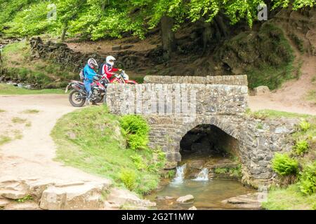 Off-Road-Motorradfahrer mit einer grünen Spur Weg überqueren die Steinbrücke an den drei Shires Kopf in der Spitze District National Park England Großbritannien Stockfoto