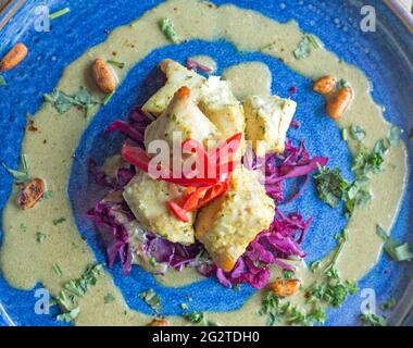 Hähnchen Satay präsentiert auf einem blauen Teller und fotografiert aus der Nähe unter natürlichem Licht. Stockfoto