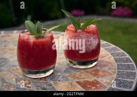 Eisiger Sommercocktail mit Erdbeere. Ein Glas Erdbeersoda auf Gartenhintergrund. Stockfoto