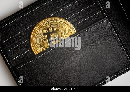Herren-Geldbörse mit Bitcoin, Draufsicht auf schwarze Geldbörse und Goldmünze (btc). Offene Ledertasche und eine Bitcoin. Konzept des virtuellen Geldes, Krypto-Curr Stockfoto