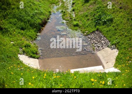Wasserablauf. Neigung, um Wasser von der Straße abzuleiten. Hydrokommunikation entlang der Autobahn. Betonabfluss. Graben zum Schutz vor Regen. Stockfoto