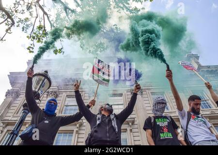 London, Großbritannien. Juni 2021. Demonstranten halten Rauchfackeln und Plakate vor der Downing Street während des Protestes der Justiz für Palästina fest. Tausende von Menschen marschierten durch London, um Gerechtigkeit für Palästina zu fordern, und forderten die G7 auf, die militärische Zusammenarbeit mit Israel zu beenden und Sanktionen gegen Israel zu verhängen. Kredit: SOPA Images Limited/Alamy Live Nachrichten Stockfoto