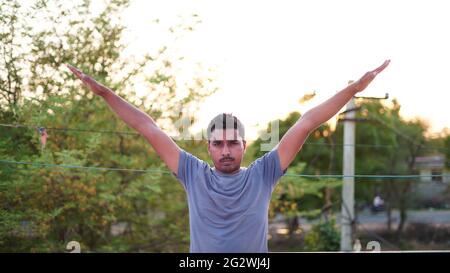 Gesunder junger Mann, der Stretching-Übungen auf grünem Gras im Park macht. Konzept des Yoga-Tages Stockfoto