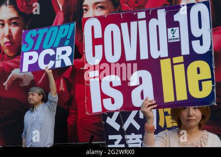 Tokio, Japan. Juni 2021. Japanische Demonstranten halten Plakate mit den Worten "Covid-19 ist eine Lüge" und "Stop PCR" auf einer kleinen Demonstration gegen die Regierung und gesellschaftliche Maßnahmen zur Bekämpfung der COVID19-Pandemie Shibuya.Anhänger von Masayuki Hiratsuka der Popular Sovereignty Party von Japan, Der 2020 erfolglos für den Gouverneur von Tokio kandidierte, veranstaltete auf dem ikonischen Hachiko-Platz ein Musikfestival, das die Coronavirus-Pandemie als Lüge bezeichnete. Kredit: SOPA Images Limited/Alamy Live Nachrichten Stockfoto