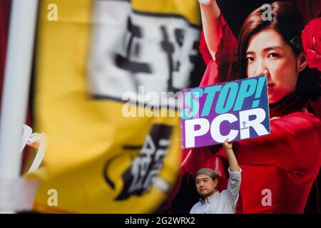 Tokio, Japan. Juni 2021. Ein Japaner hält ein Plakat mit der Aufschrift „Stop PCR“ bei einer kleinen Demonstration gegen die Regierung und gesellschaftliche Maßnahmen zur Bekämpfung der COVID19-Pandemie Shibuya.Unterstützerinnen von Masayuki Hiratsuka von der Popular Sovereignty Party von Japan, Der 2020 erfolglos für den Gouverneur von Tokio kandidierte, veranstaltete auf dem ikonischen Hachiko-Platz ein Musikfestival, das die Coronavirus-Pandemie als Lüge bezeichnete. Kredit: SOPA Images Limited/Alamy Live Nachrichten Stockfoto