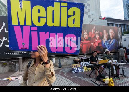 Tokio, Japan. Juni 2021. Ein Japaner hält ein Plakat mit der Aufschrift „Media Virus“ auf einer kleinen Demonstration gegen die Regierung und gesellschaftliche Maßnahmen zur Bekämpfung der COVID19-Pandemie Shibuya.die Unterstützerinnen von Masayuki Hiratsuka von der japanischen Volkssouveränität, Der 2020 erfolglos für den Gouverneur von Tokio kandidierte, veranstaltete auf dem ikonischen Hachiko-Platz ein Musikfestival, das die Coronavirus-Pandemie als Lüge bezeichnete. Kredit: SOPA Images Limited/Alamy Live Nachrichten Stockfoto