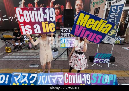 Tokio, Japan. Juni 2021. Japanische Frauen halten Plakate mit der Aufschrift „Covid-19 ist eine Lüge“ und „Medienvirus“ auf einer kleinen Demonstration gegen die Regierung und gesellschaftliche Maßnahmen zur Bekämpfung der COVID19-Pandemie Shibuya.Unterstützerinnen von Masayuki Hiratsuka der japanischen Volkssouveränität, Der 2020 erfolglos für den Gouverneur von Tokio kandidierte, veranstaltete auf dem ikonischen Hachiko-Platz ein Musikfestival, das die Coronavirus-Pandemie als Lüge bezeichnete. Kredit: SOPA Images Limited/Alamy Live Nachrichten Stockfoto