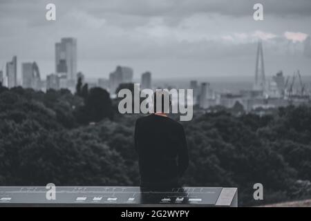 Mann in Hampstead Heath, der am Telefon telefoniert und die Skyline von London anstarrt Stockfoto