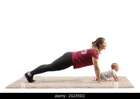 Junge Mutter macht Plank-Übungen mit ihrem Baby kriechen auf Teppich isoliert auf weißem Hintergrund Stockfoto