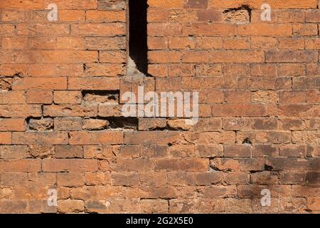 Eine Lücke in einer alten Steinmauer. Die Festungssteinmauer eines alten Schlosses mit Schlupflöchern. Kugel- und Kanonenkugel-Markierungen an der Wand. Strukturiert b Stockfoto