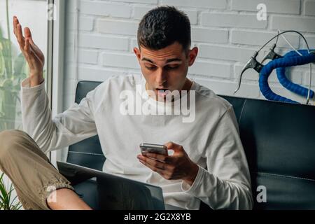 Der Mann zu Hause, der das Mobiltelefon ansah, war überrascht Stockfoto