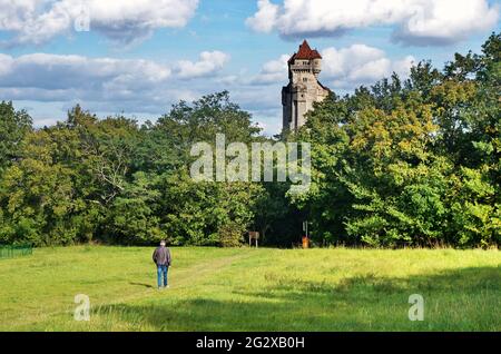 Wiese mit einem Wandermann und einem Schloss im Hintergrund. Liechtenstein Schloss aus dem 12. Jahrhundert, Schloss bei Maria Enzersdorf in Niederösterreich. Stockfoto