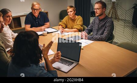 Geschäftsfrau mit Laptop diskutiert neue Ideen mit fokussierten Kollegen im Meeting. Kollegen hören weiblichen Führungskräften bei Vorstandssitzungen zu. Stockfoto