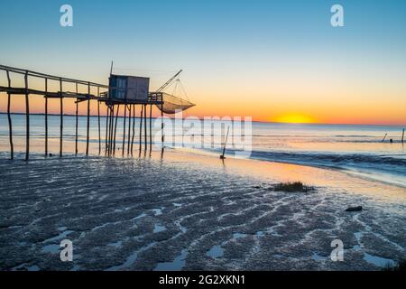 Gironde-Flussmündung mit hölzerner Angelhütte bei Sonnenuntergang am Strand bei Ebbe in Charente Maritime, Frankreich, in der Nähe von La Rochelle an der Westatlantikküste Stockfoto