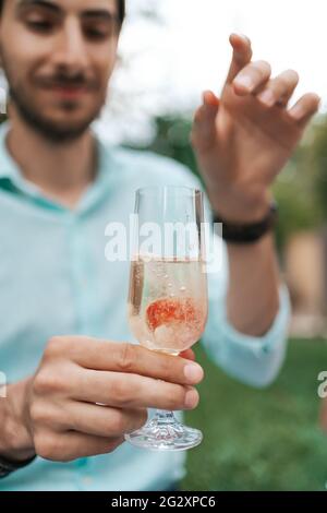 Man Hand Drop eine Erdbeere in ein Glas mit Sekt. Schönes Leben, cellebration Stockfoto