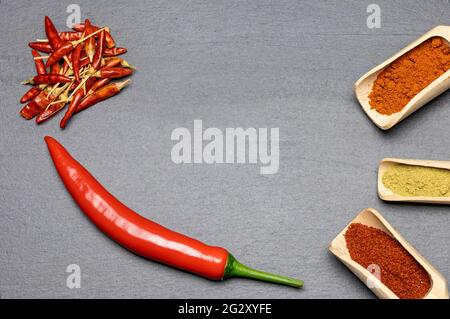 Blick von oben auf frisches, getrocknetes und gemahlenes Chili auf dem Schreibtisch. Horizontal. Stockfoto