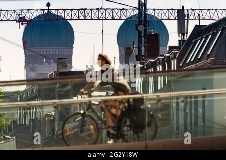 München, Deutschland. Juni 2021. Eine Frau radelt über eine Brücke, die die Landsberger Straße überspannt. Die beiden Türme der Frauenkirche im Hintergrund Credit: Peter Kneffel/dpa/Alamy Live News Stockfoto
