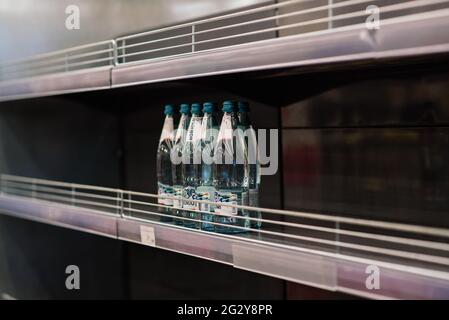 Wenige Flaschen mit Trinkwasser im Regal im Kaufhaus, Mangel an Waren Stockfoto