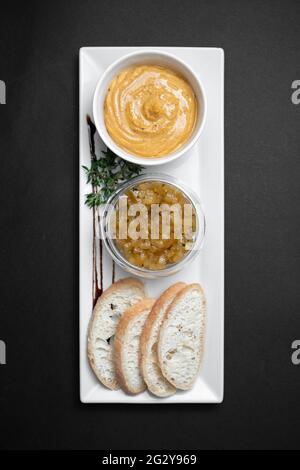 Draufsicht auf Gänseleber-Pastete mit Apfelchutneys und Brot auf schwarzem Hintergrund Stockfoto